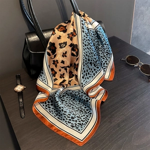 Detailed macro shot of a silk scarf featuring orange and blue leopard print on a black bag