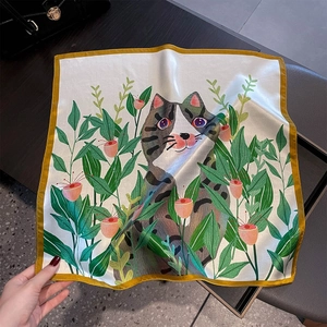 Close-up of silk square scarf featuring artistic cat and floral prints with golden edges