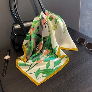 Elegant silk scarf with panda and floral prints draped on a black leather handbag