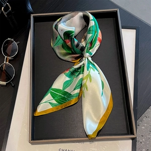 Close-up of a floral silk scarf with a pearl buckle fastener on a luxury display tray