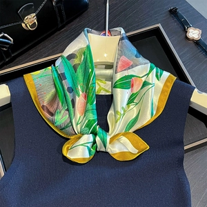 Detail of silk scarf with green tropical leaves and yellow border on a hanger