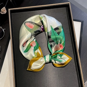 Elegant silk scarf featuring vibrant botanical prints and cats, displayed on a stylish tray