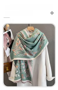 Detail of floral imitation cashmere scarf with tassels styled on a white coat