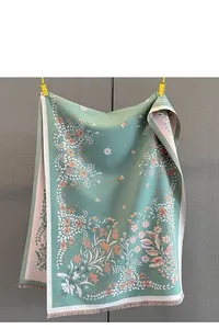 Detail of floral jacquard scarf fabric with delicate tassels and elegant grey-green pattern