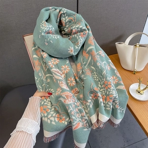 Detail of floral jacquard mint green scarf with orange bird patterns and brown tassels