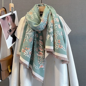Detailed view of floral jacquard scarf with fringe trim draped over a coat