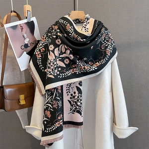 Detail of floral jacquard scarf with delicate fringe edges on a white coat background