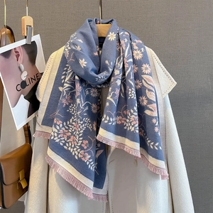 Elegant floral jacquard scarf in dusty blue with pink tassel edges on a wool coat