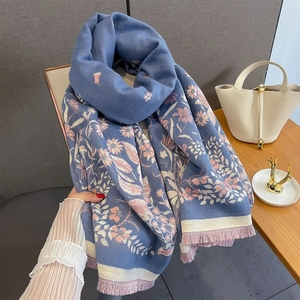 Detail of blue floral shawl with pink flower jacquard and purple tassels on wood table