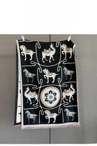 Macro view of animal jacquard knit scarf featuring horse and camel motifs with tassels