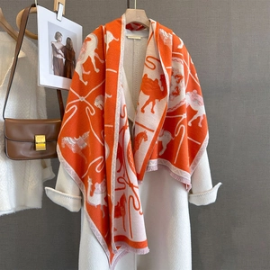 Orange and beige animal pattern jacquard knit scarf with tassels over a white coat