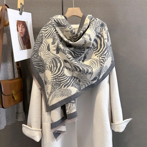 Detailed view of zebra print cashmere-like scarf with soft frayed edges on a coat