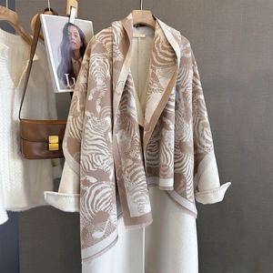 Detailed texture of zebra print faux cashmere scarf draped over a cream winter coat