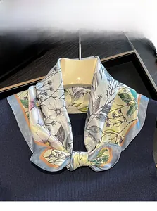 Detail of 100% mulberry silk scarf with floral patterns tied as a bow on a black collar