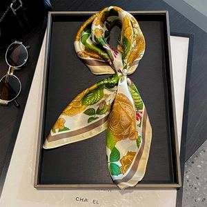 Detail of silk scarf with vintage rose pattern and pearl buckle on a display tray
