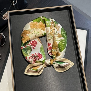 Detail of a floral silk scarf with cream base and red-yellow flowers on a handbag