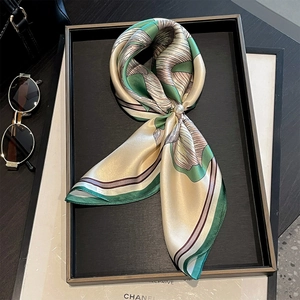 Elegant silk scarf with geometric stripes and pearl buckle on a minimalist tray
