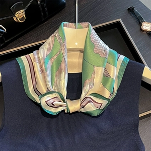 Detail of silk scarf tied as a bow on a navy top with geometric patterns and luxury items