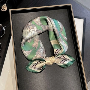 Elegant mulberry silk neck scarf with green leaf pattern displayed on a luxury tray