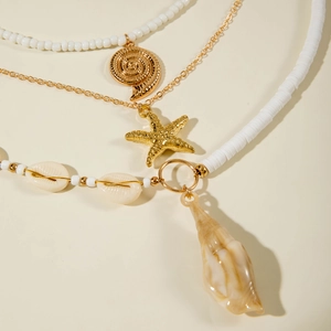 Λεπτομέρεια από πολυεπίπεδο κολιέ boho με μενταγιόν αστερία και κοχύλι
