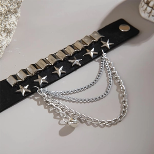 Detail of punk black PU leather cuff with silver stars, rivets, chains and small bell charm