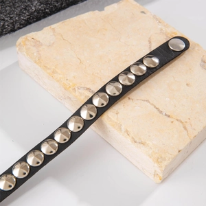 Close-up of black punk PU leather bracelet with silver metal rivets on a stone prop