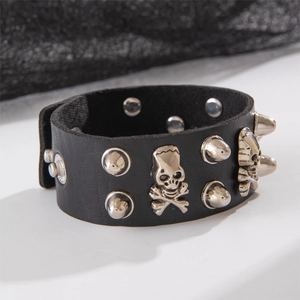 Detail view of punk black leather cuff bracelet featuring silver studs and skull emblem