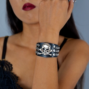 Detail of punk leather bracelet featuring a silver skull, rivets, and triple chains