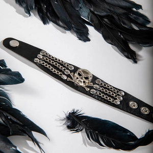 Detail of punk black leather cuff with silver skull motif, chains and metal studs