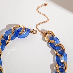 Chunky gold chain necklace with blue acrylic links and lobster clasp on white background