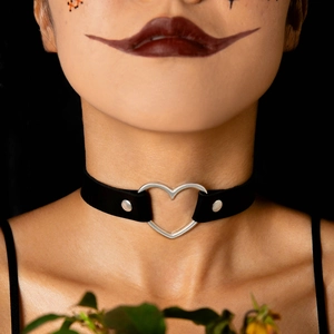 Dettaglio di un choker punk nero con un ornamento in metallo a forma di cuore d'argento