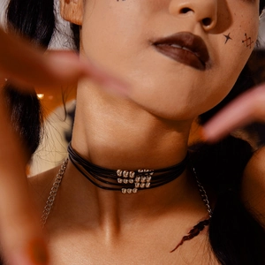 Dettaglio di un choker punk nero a più strati con perle di metallo argento sul collo