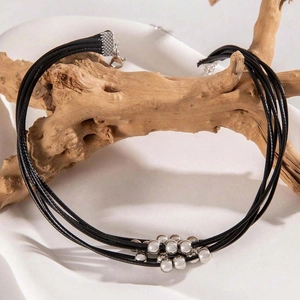 Dettaglio della collana a più fili neri con pendenti a sfera in metallo argento