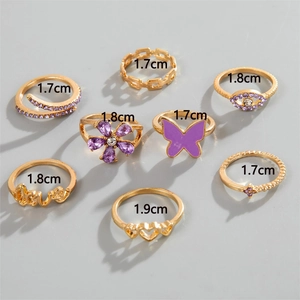 Detailed set of eight gold-finish rings featuring purple gems, enamel, and love motifs
