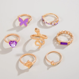 Detail of 7-piece gold ring set featuring purple butterfly, snakes, and heart gems
