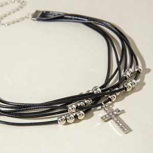 Dettaglio della collana multi-filo in cordino nero con croce di cristallo e catena regolabile