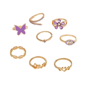 8-piece gold-tone ring set featuring purple butterflies, hearts, and rhinestones