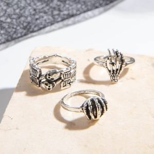 Detailed view of three gothic silver rings with skull and skeleton hand designs on stone