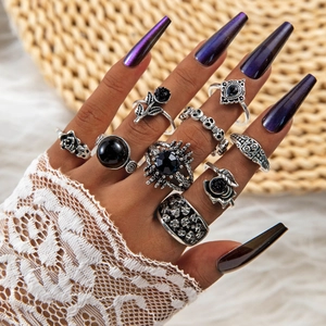 Close-up of punk style silver skull rings with black gems worn in a layered goth set