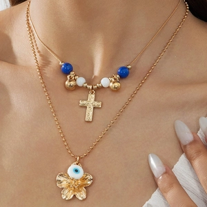 Mehrlagige Goldkette mit Kreuzanhänger und Evil Eye Blumenanhänger an einem Modell