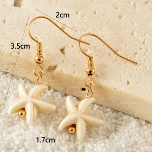 Detail of bohemian starfish earrings with gold hooks and textured shell-like finish