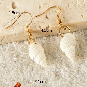 Detail view of Bohemian seashell earrings with dimensions shown on a sandy beach