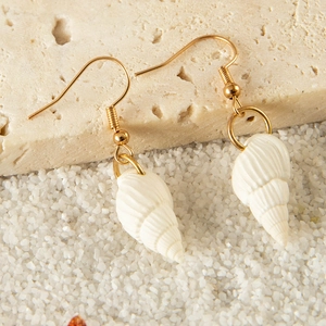 Bohemian seashell and starfish drop earrings on beach sand and rock surface