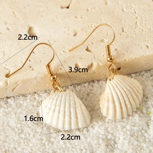 Detail view of shell earrings with dimensions 3.9cm length on beach stone background