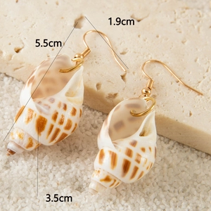 Detail view of shell earrings with size dimensions 5.5cm on a sandy beach background