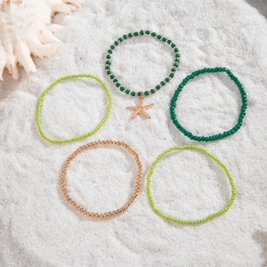 Detail of 5-piece beach anklet set featuring starfish charm and colorful seed beads on sand