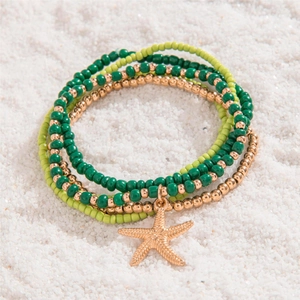Close-up of bohemian green beaded anklet set with starfish charm on beach sand
