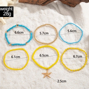 Detail view of 6-piece bohemian shell and starfish anklet set with sizes on beach sand