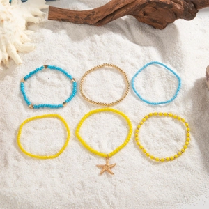 Detail of bohemian shell anklet set with starfish charm on white beach sand background