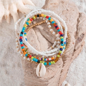 Detail of bohemian layered anklets with colorful seed beads and a natural shell charm